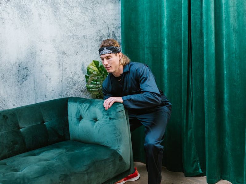 Man performing a controlled bodyweight exercise in a minimalist room.